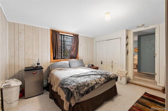 bedroom with wood walls, a closet, and fridge