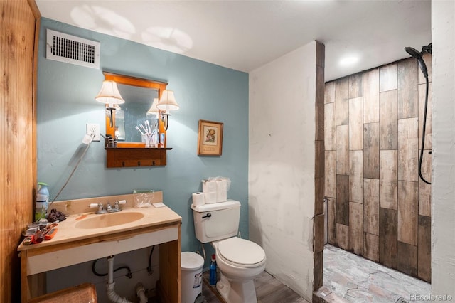 bathroom with vanity, toilet, visible vents, and tiled shower