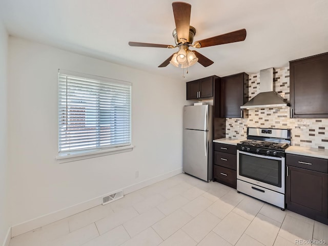 kitchen with visible vents, baseboards, wall chimney range hood, appliances with stainless steel finishes, and tasteful backsplash