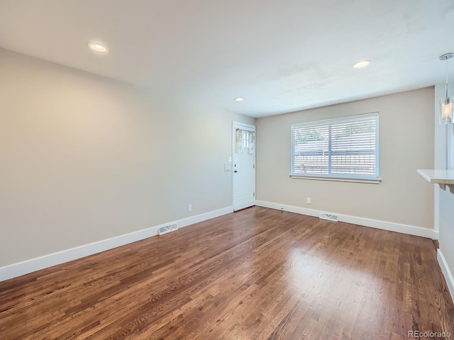 unfurnished living room featuring baseboards, dark wood-style flooring, recessed lighting, and visible vents