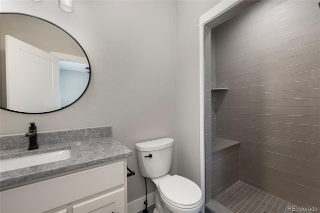 bathroom with vanity, toilet, and a tile shower