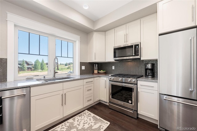 kitchen featuring light stone countertops, premium appliances, white cabinetry, and sink