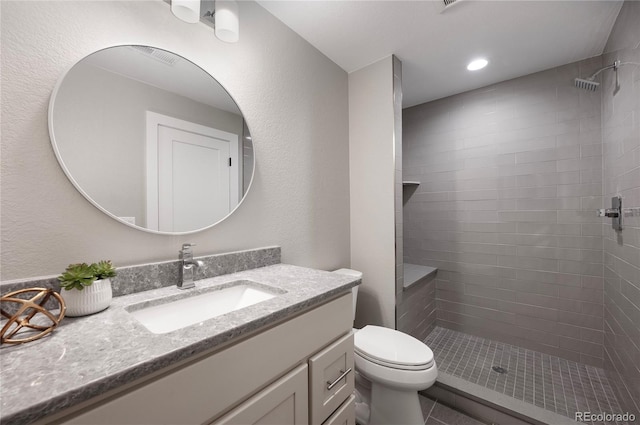 bathroom featuring vanity, toilet, and tiled shower