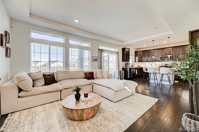 living room with recessed lighting, a raised ceiling, and dark wood finished floors