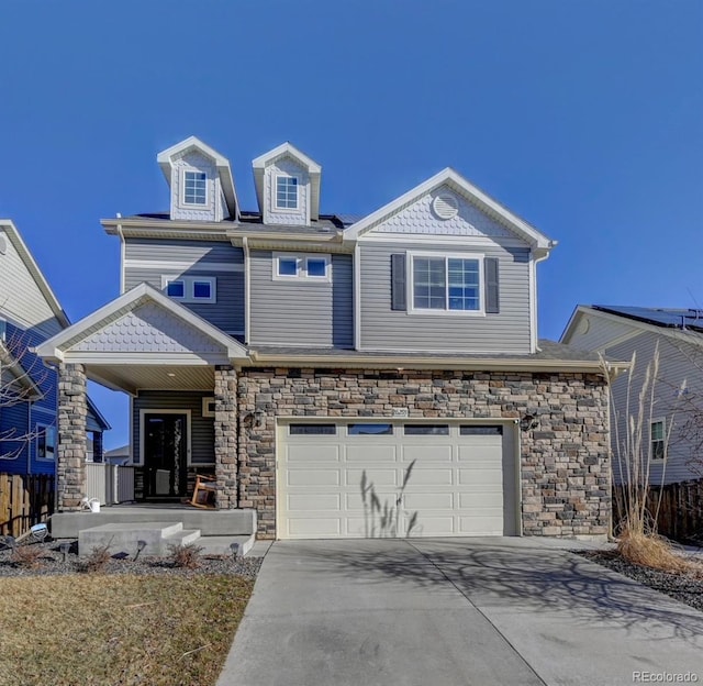 view of front of home featuring covered porch, fence, a garage, stone siding, and driveway