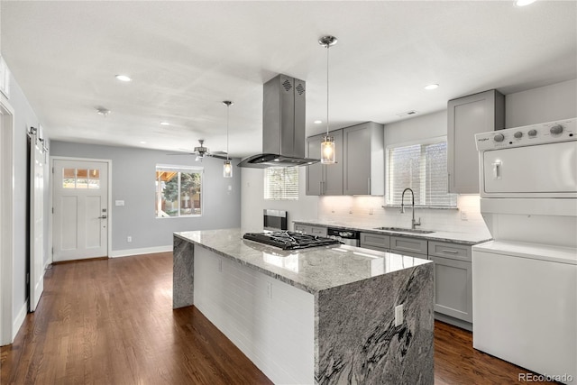 kitchen with a sink, gray cabinets, estacked washer and dryer, island range hood, and gas stovetop
