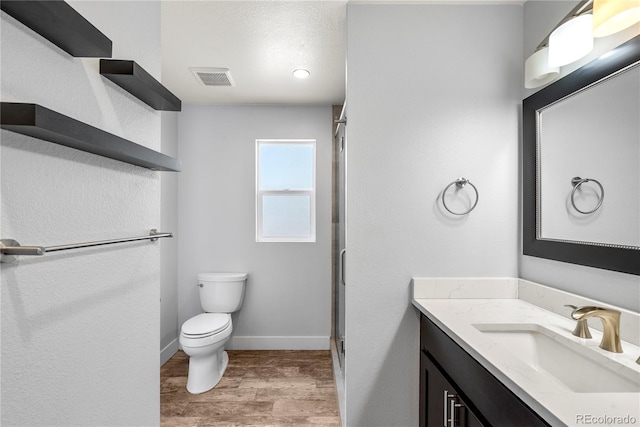 full bathroom featuring wood finished floors, a shower stall, toilet, vanity, and baseboards