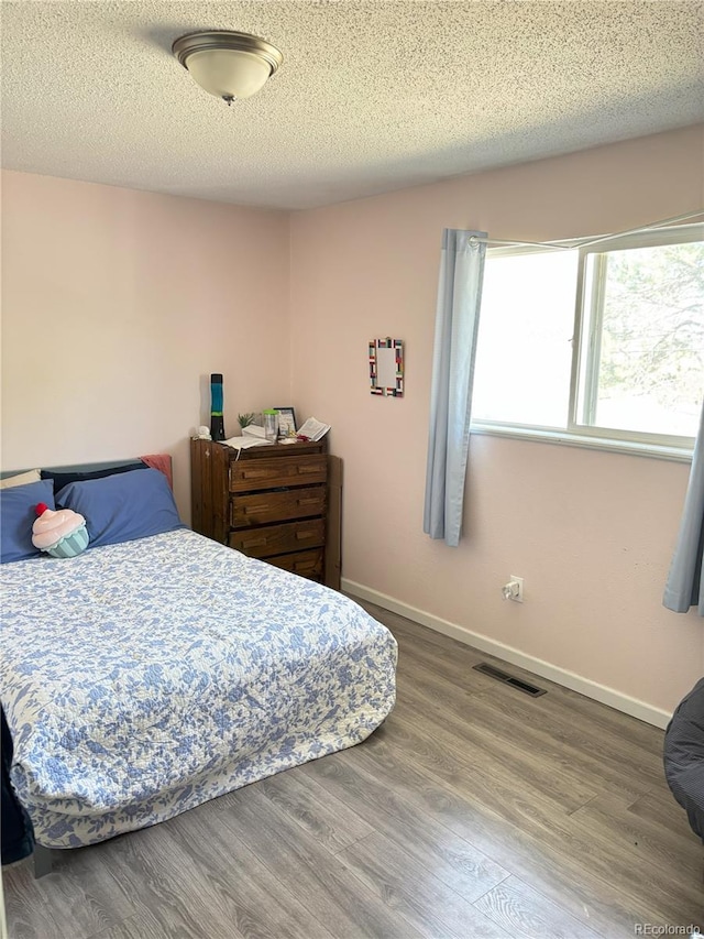 428 Prospect Ave, La Junta, CO 81050 - bedroom with visible vents, a textured ceiling, baseboards, and wood finished floors