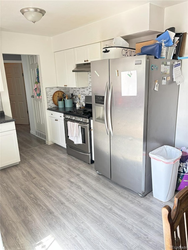 428 Prospect Ave, La Junta, CO 81050 - kitchen featuring dark countertops, light wood-type flooring, under cabinet range hood, white cabinets, and appliances with stainless steel finishes