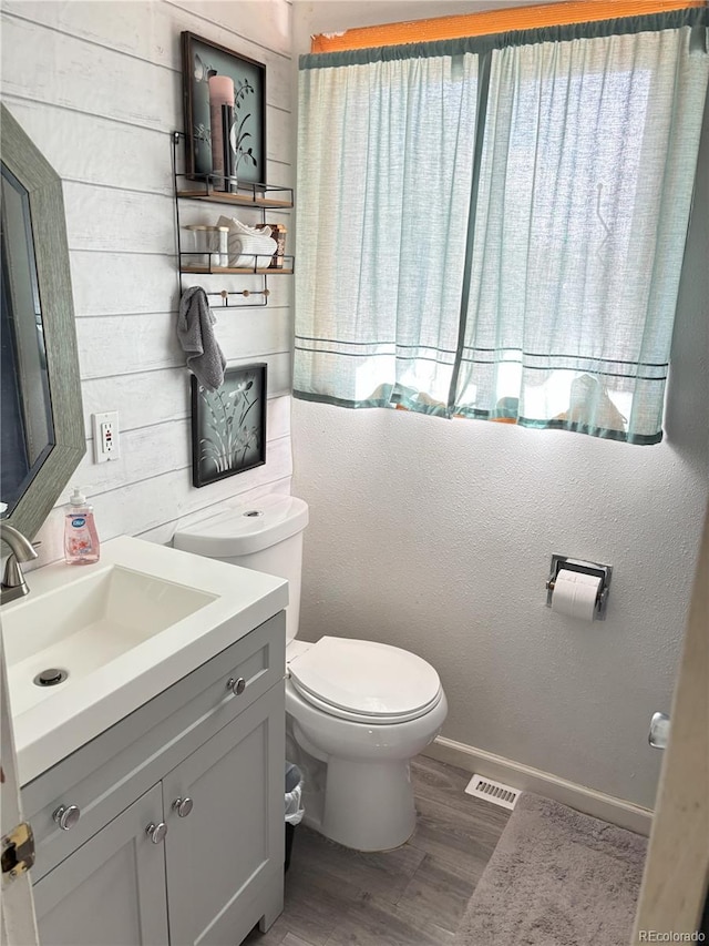 428 Prospect Ave, La Junta, CO 81050 - half bathroom featuring visible vents, wood finished floors, vanity, baseboards, and toilet