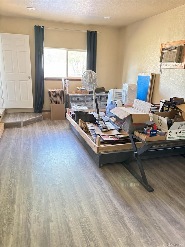 428 Prospect Ave, La Junta, CO 81050 - living area featuring a textured ceiling, a textured wall, a wall mounted AC, and wood finished floors