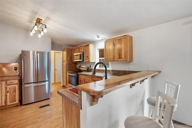 840 Obsidian Dr, Florissant, CO 80816 - kitchen featuring stainless steel appliances, a kitchen breakfast bar, light wood finished floors, and a peninsula