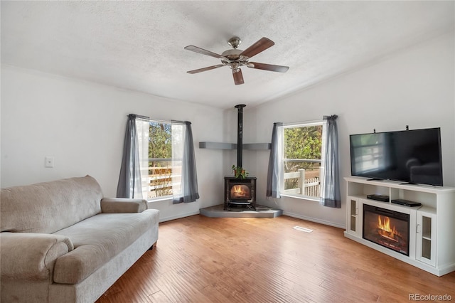 840 Obsidian Dr, Florissant, CO 80816 - living area featuring a textured ceiling, ceiling fan, healthy amount of natural light, a wood stove, and wood finished floors