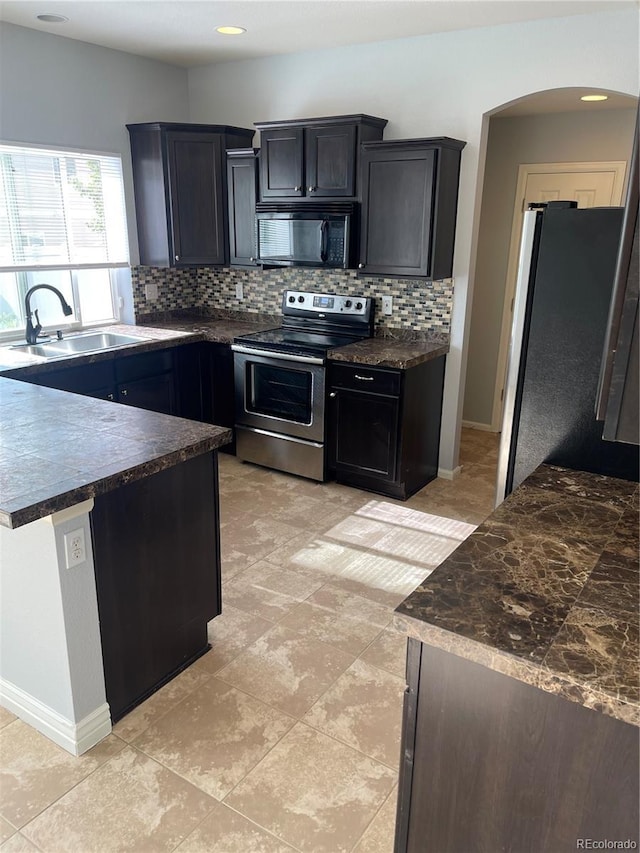 5537 Malta St, Denver, CO 80249 - kitchen with stainless steel appliances, a sink, dark countertops, backsplash, and arched walkways