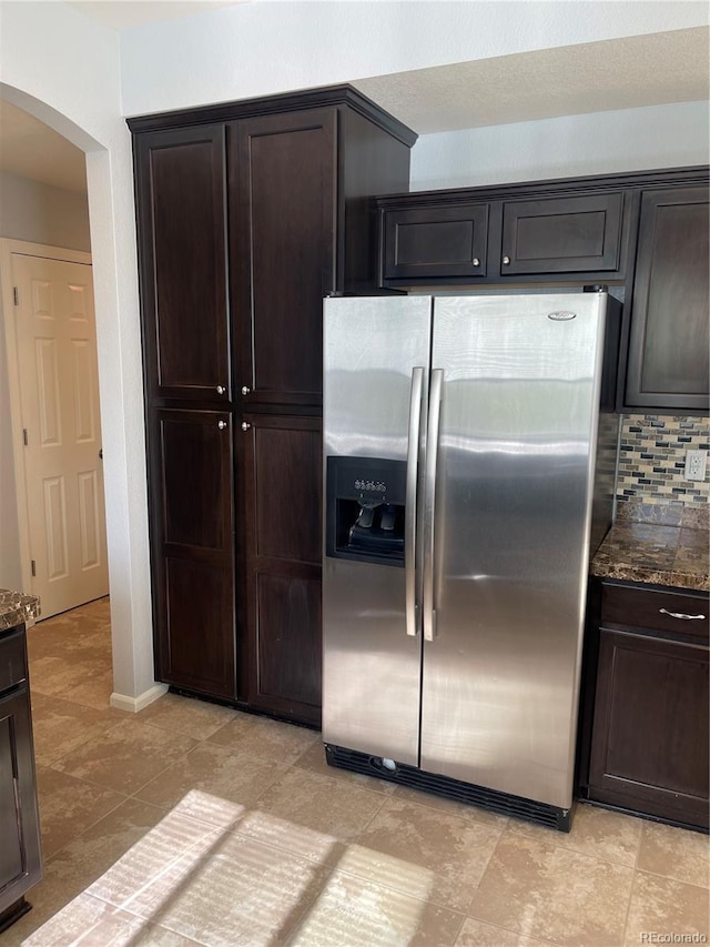 5537 Malta St, Denver, CO 80249 - kitchen with stainless steel fridge with ice dispenser, arched walkways, dark stone counters, and dark brown cabinetry