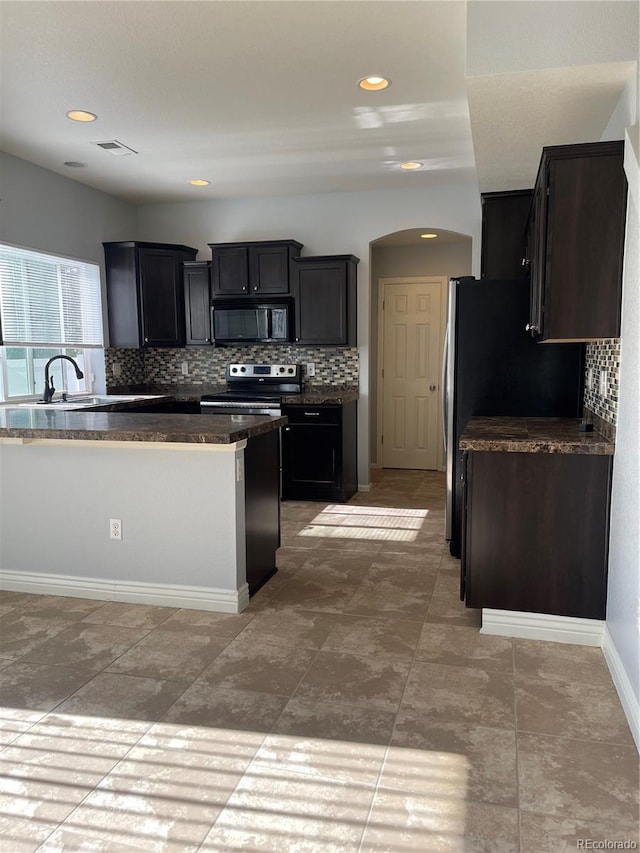 5537 Malta St, Denver, CO 80249 - kitchen featuring electric stove, black microwave, backsplash, arched walkways, and a sink