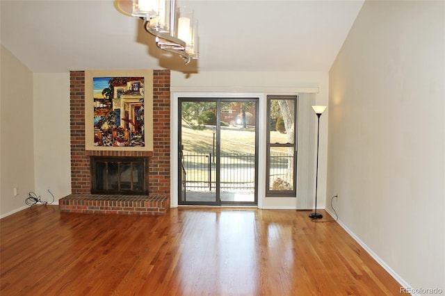 unfurnished living room with a fireplace, baseboards, and wood finished floors