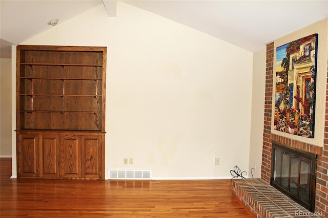 unfurnished living room featuring lofted ceiling, wood finished floors, visible vents, a brick fireplace, and baseboards