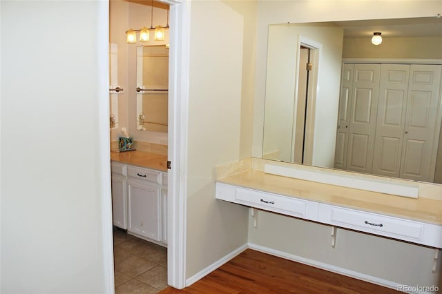 interior space with a closet, wood finished floors, baseboards, and vanity