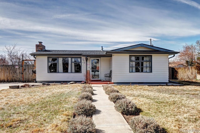 ranch-style house featuring a chimney, a front yard, and fence