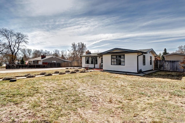 ranch-style house featuring a chimney, a front yard, and fence