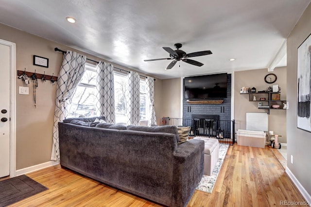 living area with recessed lighting, light wood finished floors, baseboards, a brick fireplace, and ceiling fan