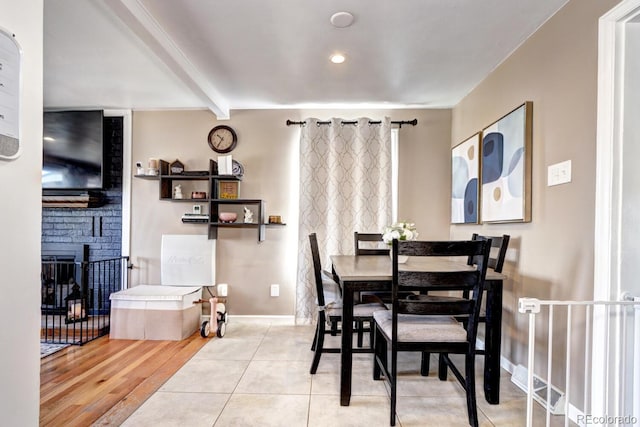 dining room with beamed ceiling, baseboards, a fireplace, and tile patterned flooring