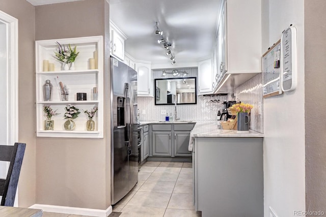 kitchen with light tile patterned flooring, stainless steel fridge with ice dispenser, gray cabinets, a sink, and backsplash