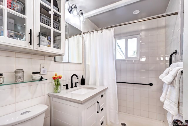 full bath with toilet, backsplash, a tile shower, tile walls, and vanity