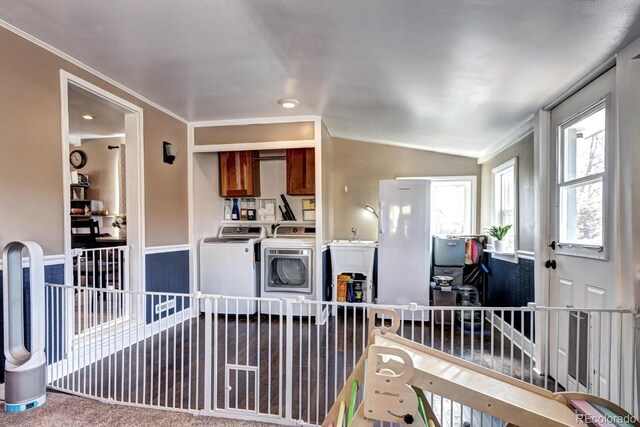 interior space with vaulted ceiling, ornamental molding, and washing machine and clothes dryer