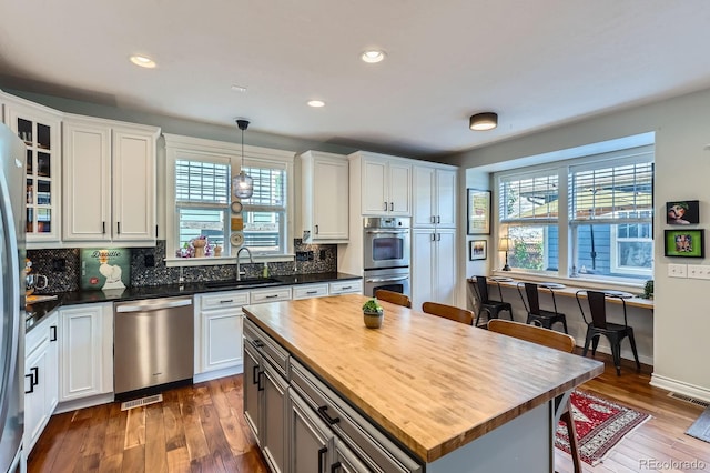 3386 Beeler Ct, Denver, CO 80238 - kitchen with stainless steel appliances, wooden counters, a sink, a breakfast bar, and white cabinetry