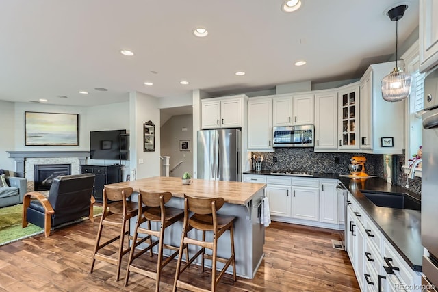 3386 Beeler Ct, Denver, CO 80238 - kitchen featuring appliances with stainless steel finishes, wood finished floors, tasteful backsplash, glass insert cabinets, and a breakfast bar area