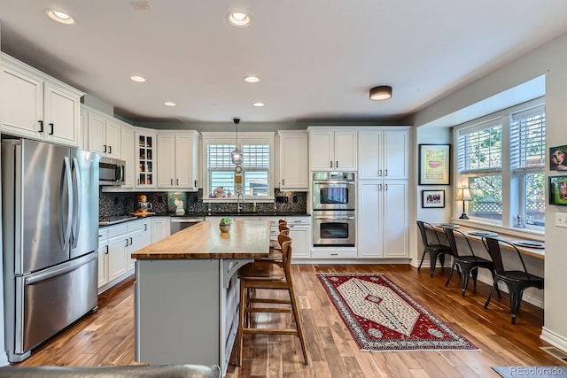 3386 Beeler Ct, Denver, CO 80238 - kitchen featuring appliances with stainless steel finishes, wood counters, plenty of natural light, white cabinetry, and recessed lighting