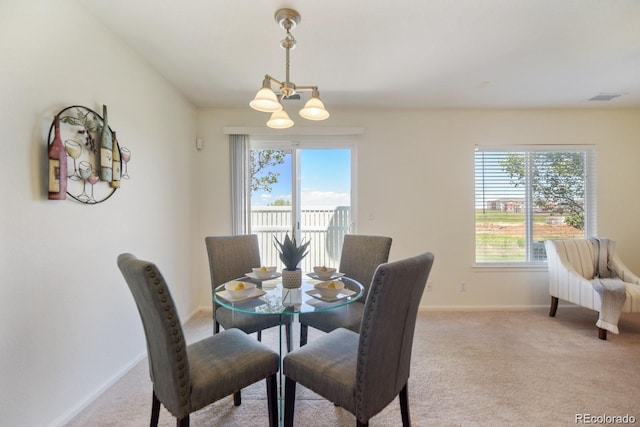 dining area with plenty of natural light, light colored carpet, and a notable chandelier