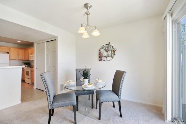 carpeted dining area featuring a chandelier