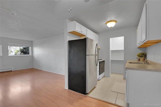 kitchen featuring a textured ceiling, a sink, white cabinets, electric stove, and freestanding refrigerator