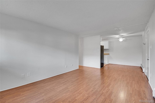 unfurnished room with a textured ceiling, light wood-type flooring, and a ceiling fan