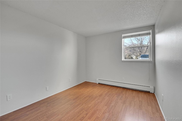 spare room featuring a baseboard radiator, a textured ceiling, and wood finished floors