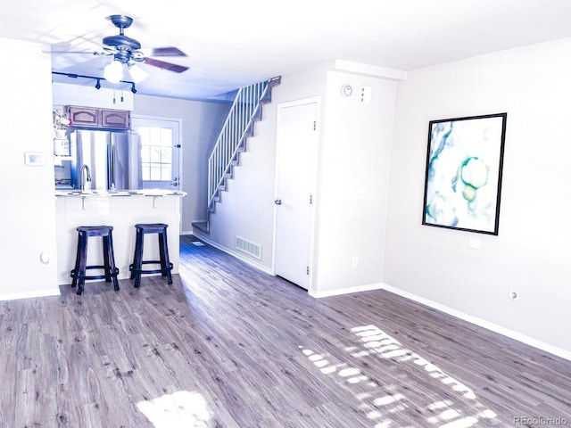 15475 E Louisiana Ave, Aurora, CO 80017 - unfurnished living room with ceiling fan, wood finished floors, stairs, baseboards, and a sink