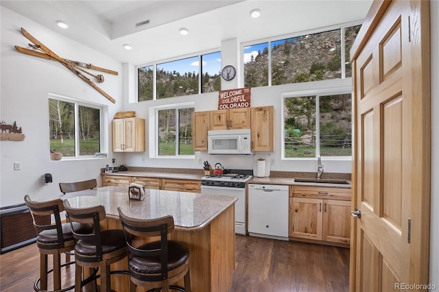 437 Langnis Rd, Guffey, CO 80820 - kitchen featuring white appliances, a high ceiling, a sink, a breakfast bar, and dark wood-type flooring