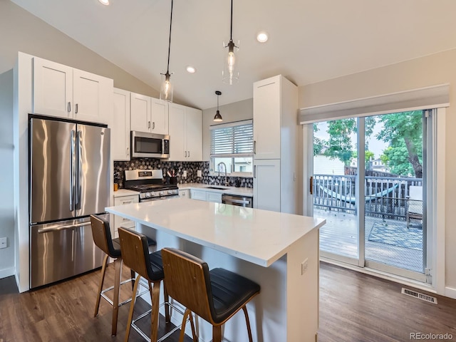 12646 Osceola St, Broomfield, CO 80020 - kitchen with appliances with stainless steel finishes, dark wood-style floors, decorative backsplash, lofted ceiling, and a breakfast bar