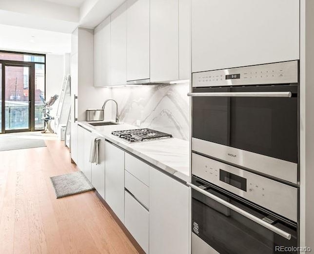 1901 Wazee St Unit 419, Denver, CO 80202 - kitchen featuring light wood finished floors, white cabinets, modern cabinets, and tasteful backsplash