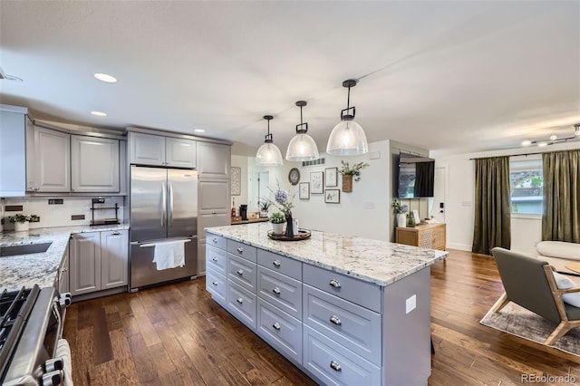 7746 S Gray St, Littleton, CO 80128 - kitchen featuring appliances with stainless steel finishes, gray cabinetry, a kitchen island, dark wood finished floors, and light stone countertops