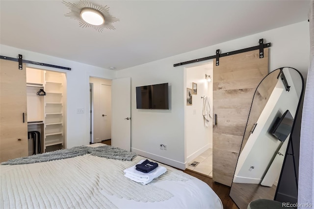 7746 S Gray St, Littleton, CO 80128 - bedroom with a barn door, a walk in closet, dark wood finished floors, baseboards, and a closet
