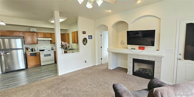 carpeted living room featuring a tile fireplace, a sink, and baseboards