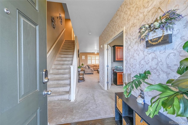 carpeted foyer featuring wallpapered walls and stairs