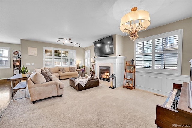 living area with visible vents, a fireplace with flush hearth, and an inviting chandelier