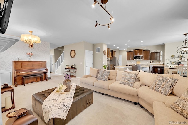 living room featuring visible vents, stairs, a chandelier, light carpet, and recessed lighting
