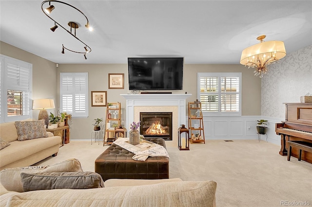 living room featuring carpet floors, a fireplace with flush hearth, wainscoting, and a chandelier
