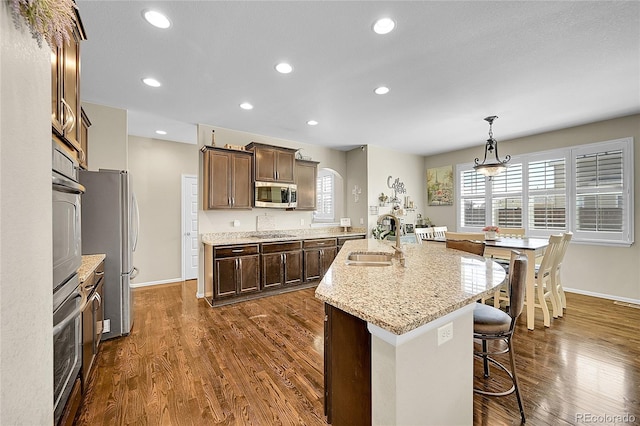 kitchen featuring a sink, dark wood finished floors, a kitchen bar, and stainless steel appliances